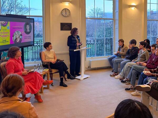 Niamh Ni Mhaoileoin and Professor Kathleen Cummings at a Notre Dame O'Connell House book event, with a speaker at the podium.